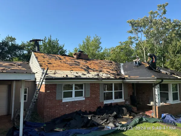 Brick ranch home with old shingles being torn off the roof