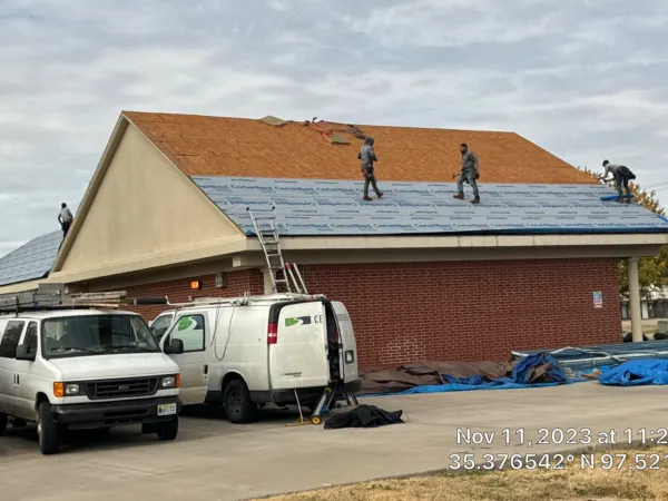 Commercial roof replacement in progress with work trucks on site