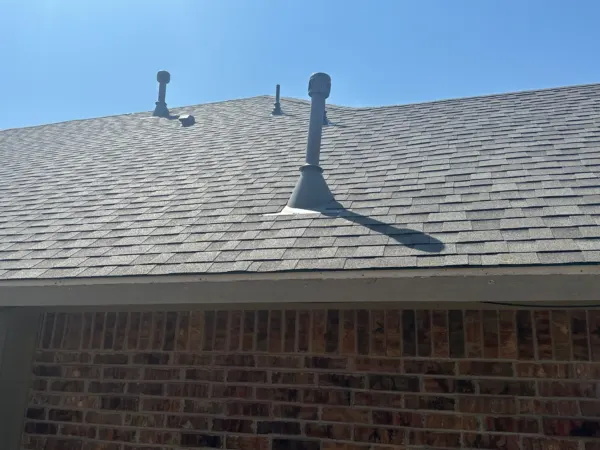 Pipe vents on the finished roof above brick walls