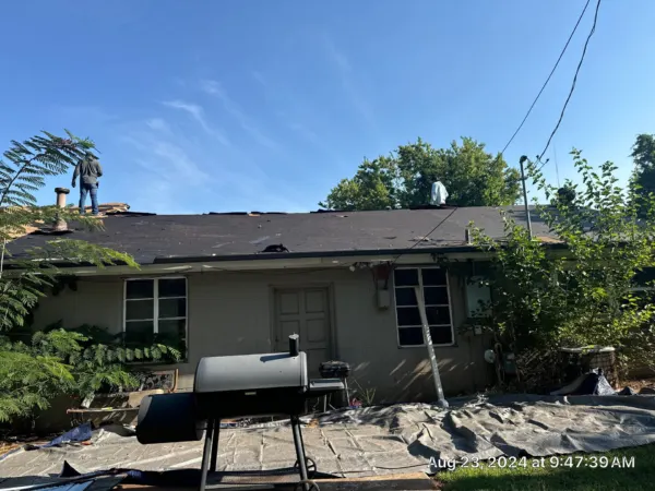 Back of the home during roof tear-off with debris protection on the ground
