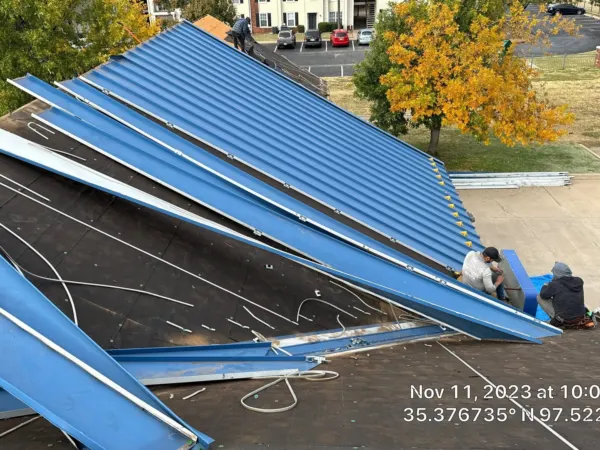 Blue metal roof panels being removed from the commercial building
