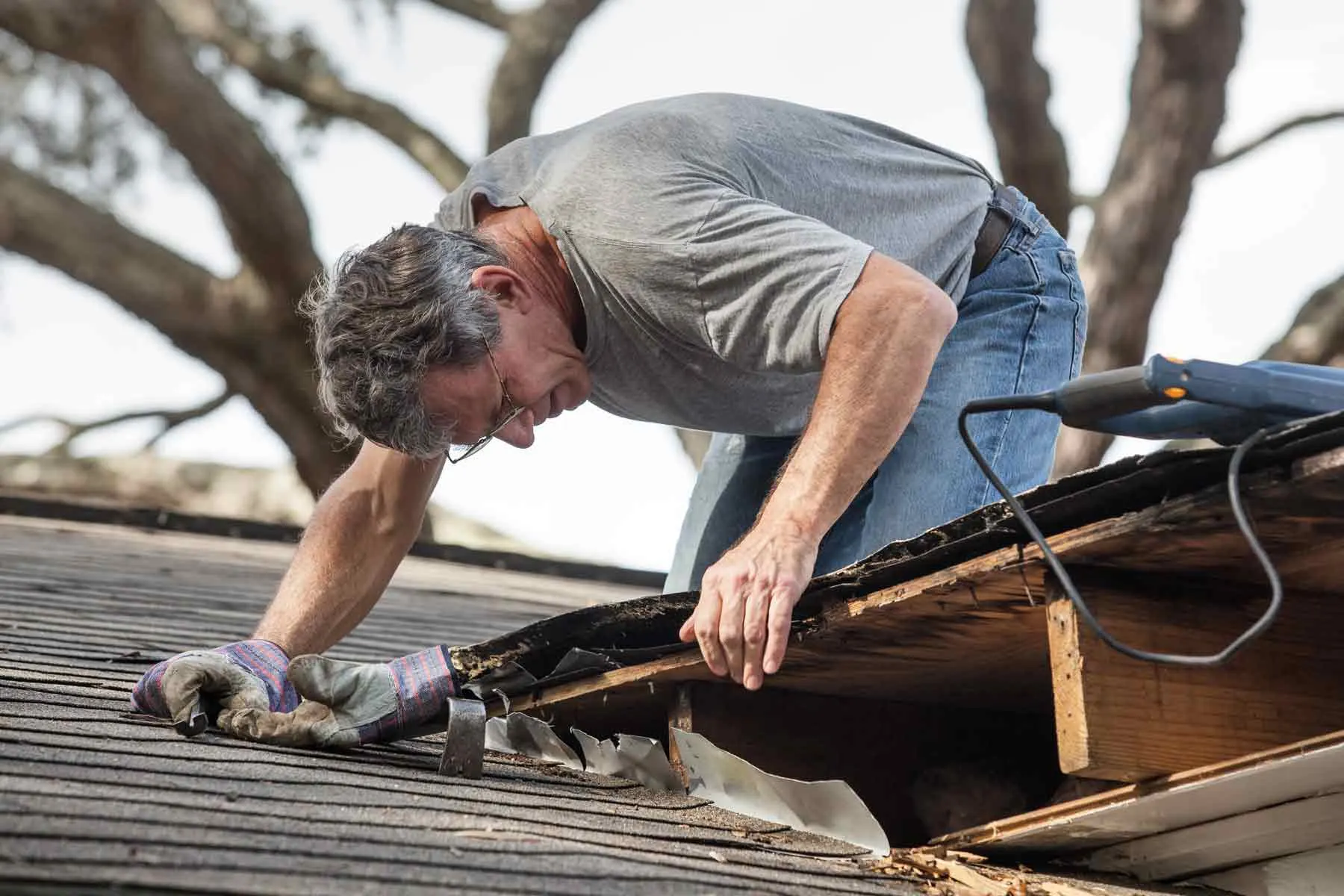 Edmond OK Roof Flashing Repair by Roof One showing a contractor inspecting damaged metal flashing and shingles on a home.